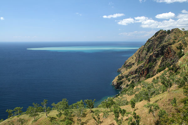 Hill above aqua blue sea
